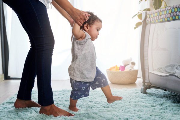 How can I help my baby walk without support and what precautions should I take?