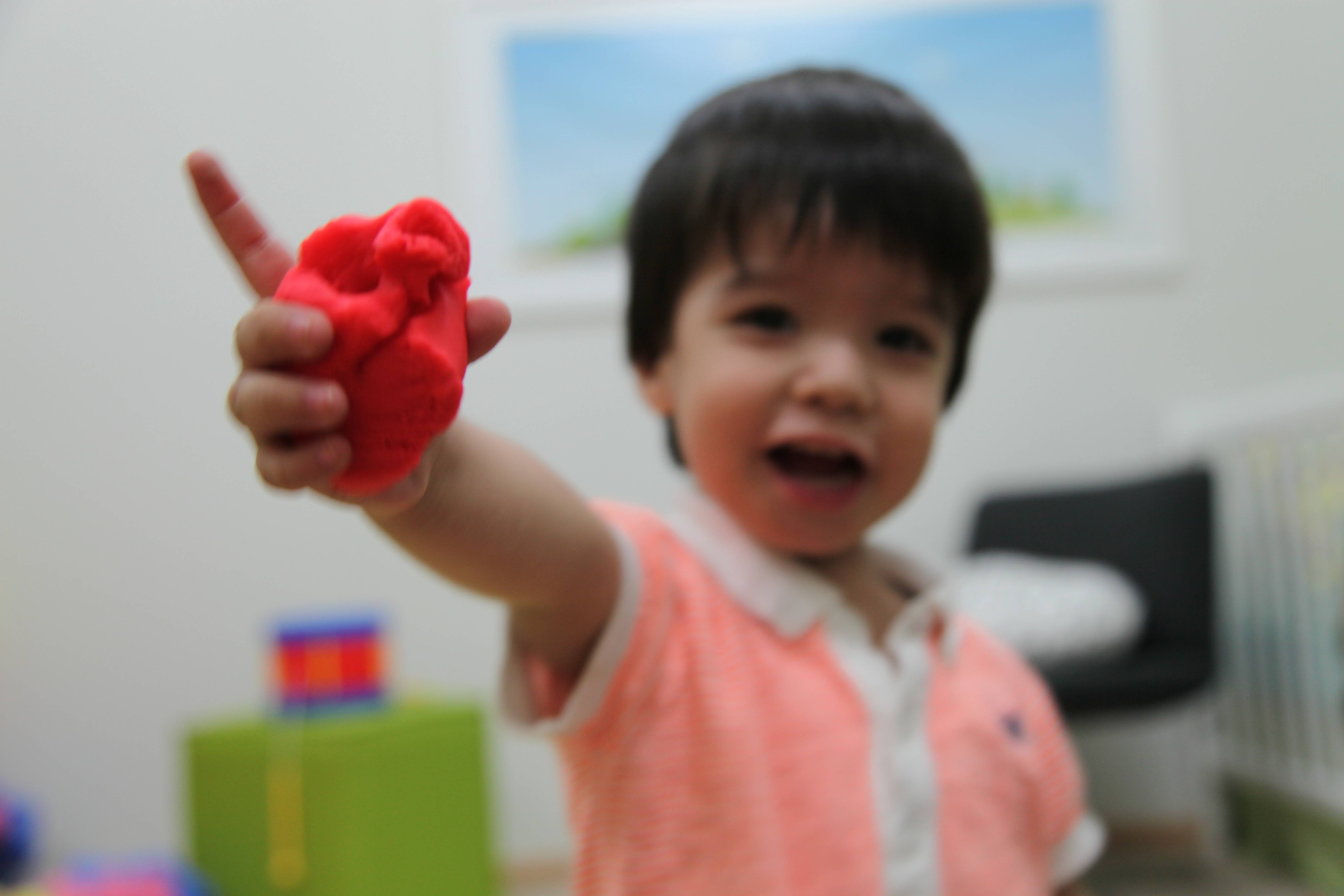 Little boy showing some red playdough