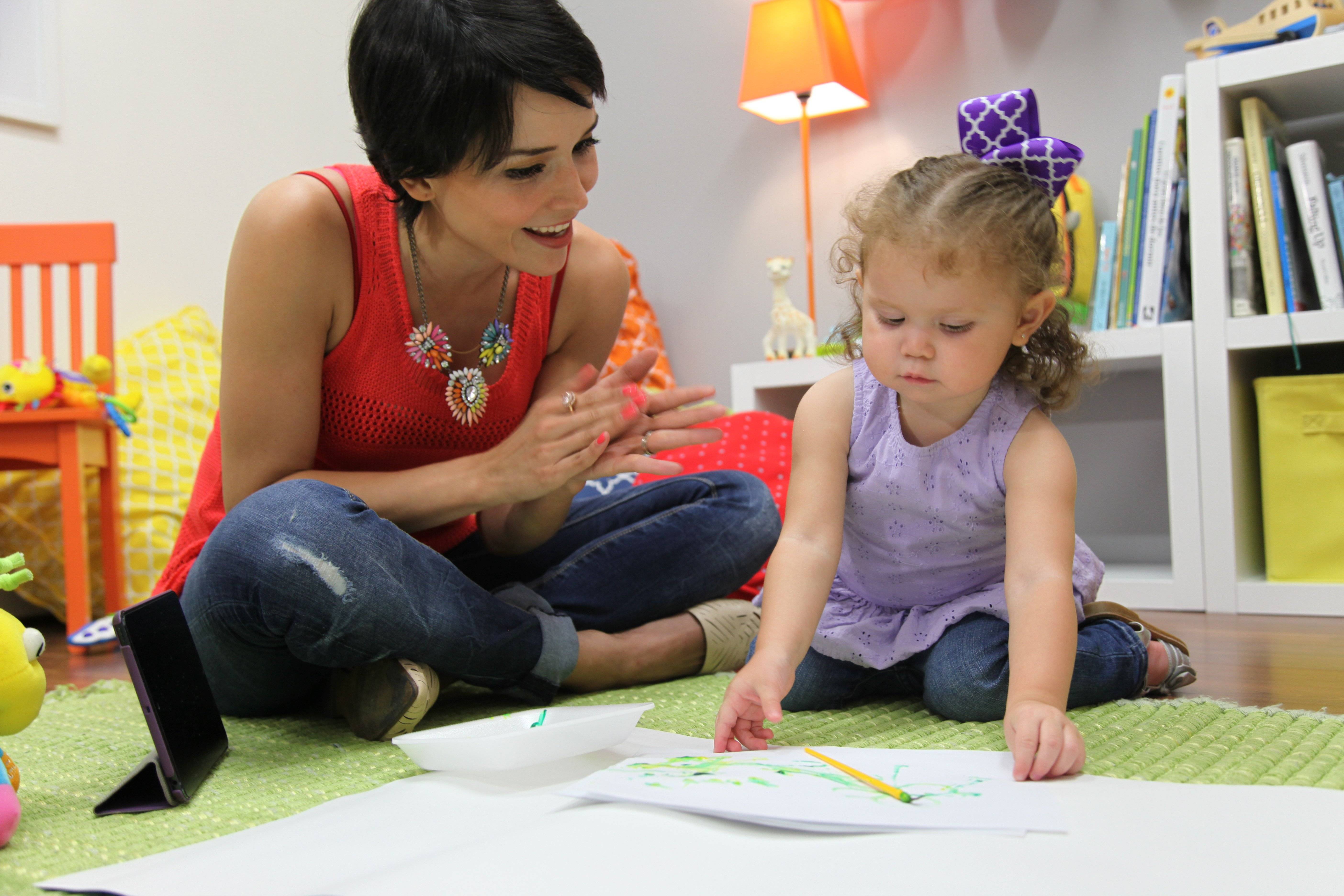 mom claps while little girl shows a drawing