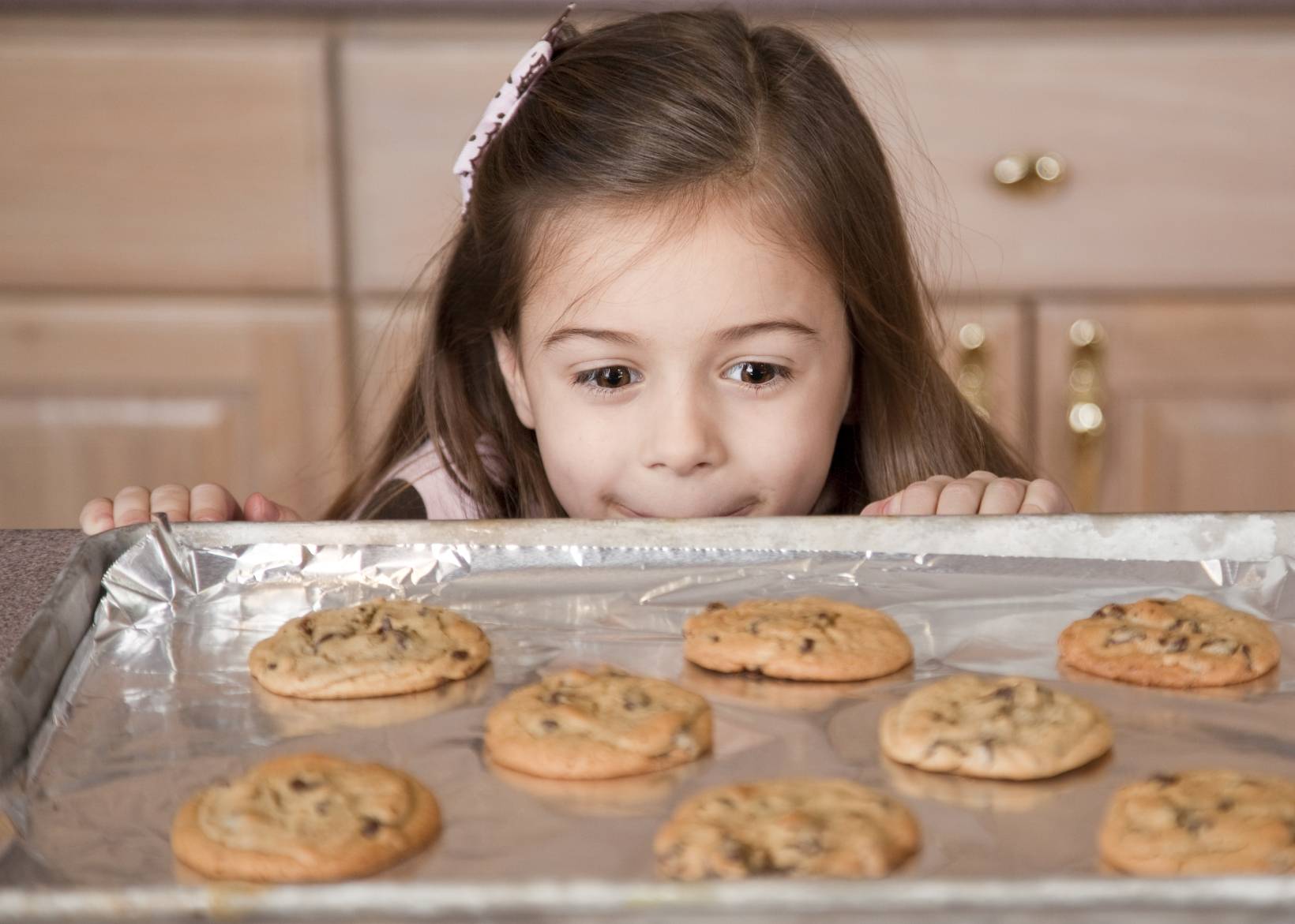 little girl staring happily at some home-made cookies