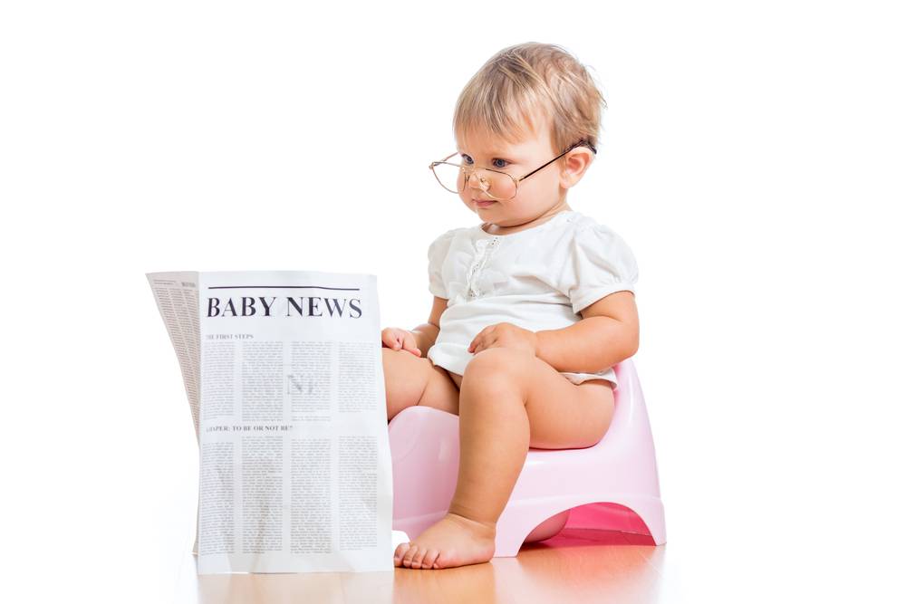 baby girl sitting on potty reading a newspaper