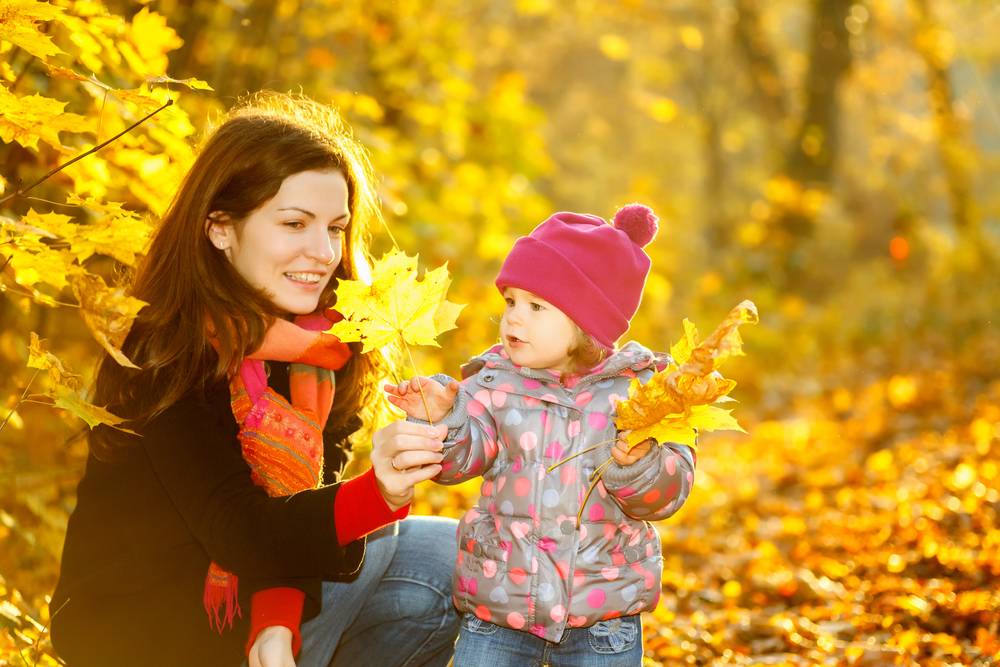 mother and little girl collecting leaves during fall