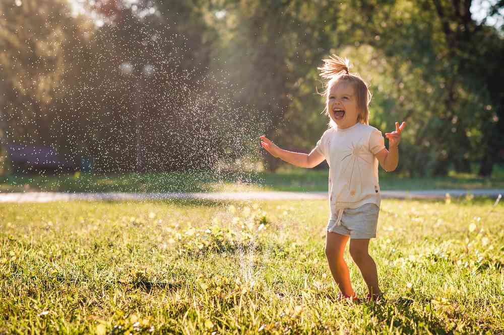 little girl laughing and playing with water