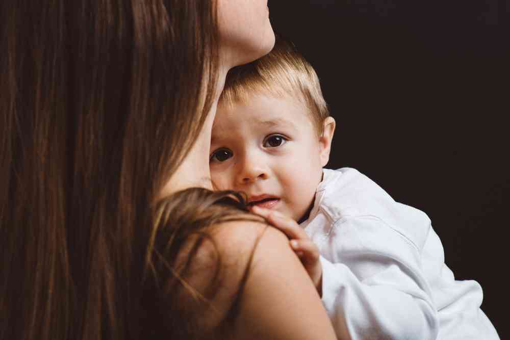 little boy in his mom's arms because he has separation anxiety