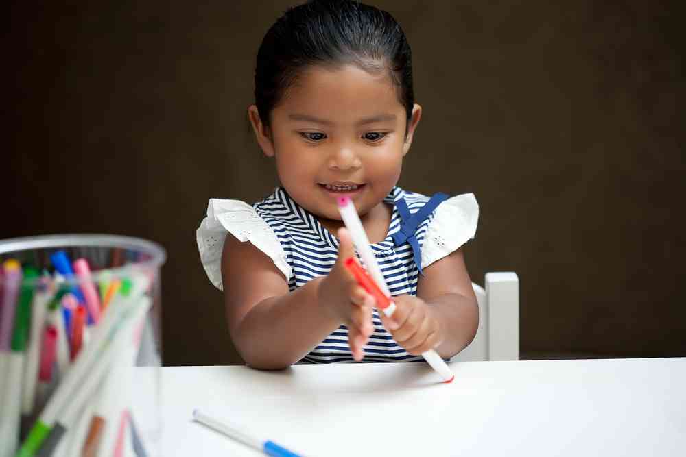 little girl playing with markers