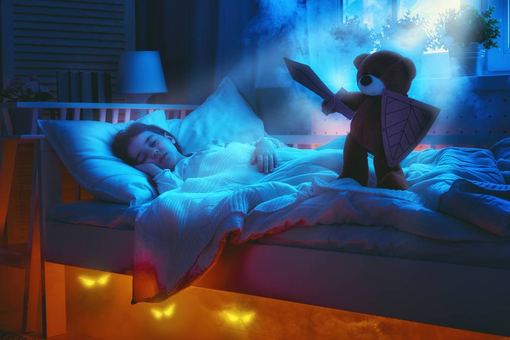 little girl sleeping while her teddy bear watches over her