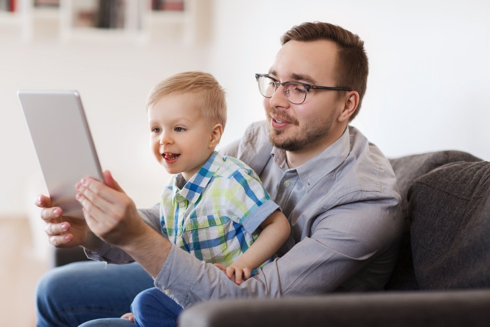 father and toddler using a tablet to video chat