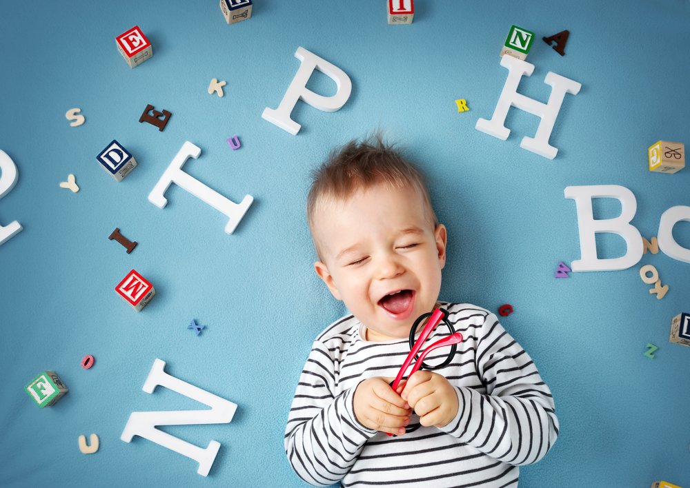 little boy laughing surrounded by letters