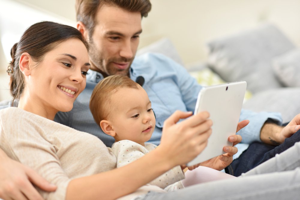 parents and toddler using a tablet together