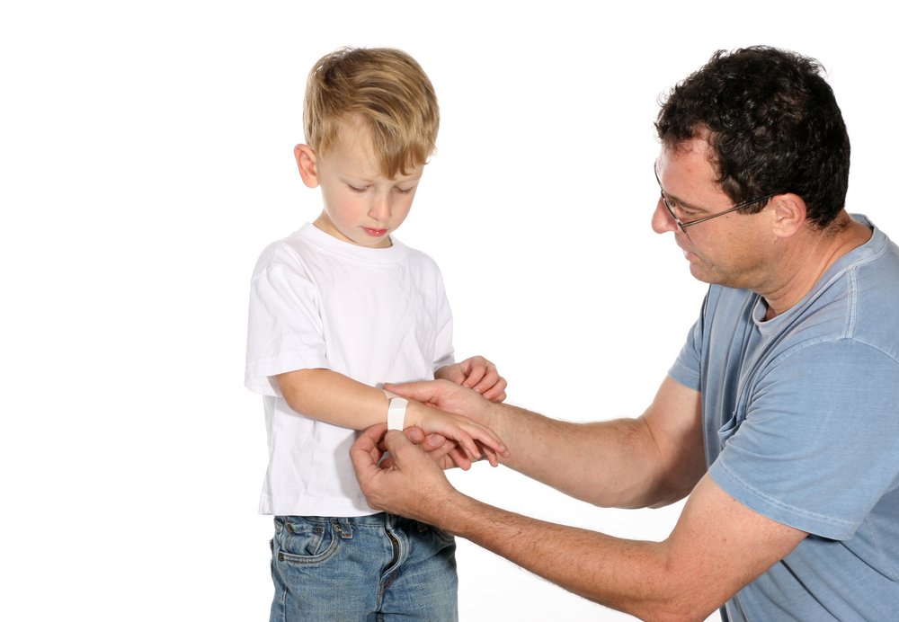 dad putting a bandaid on his son's cut