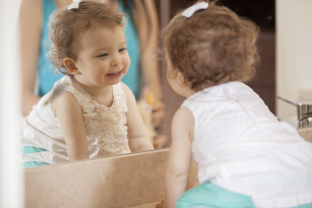 little girl smiling at her reflection