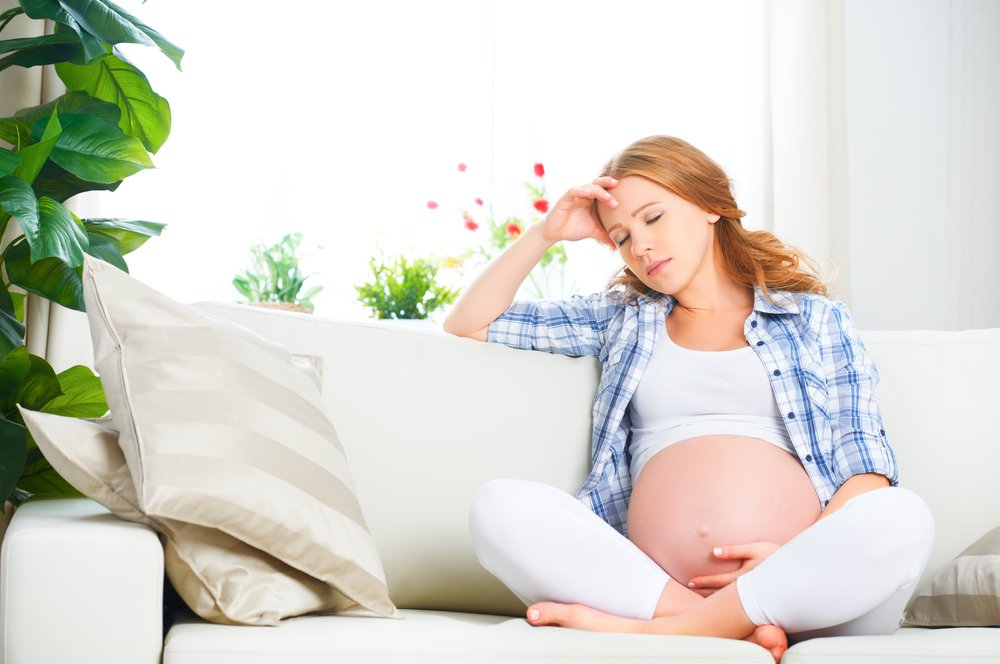 tired pregnant woman holding her head