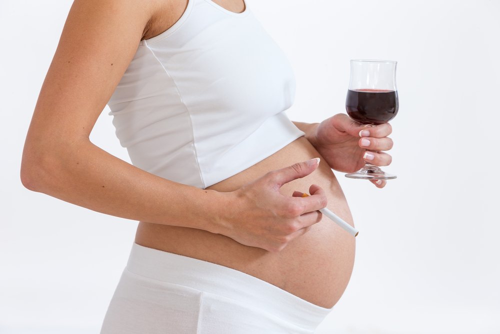 pregnant woman holding a glass of wine and a cigarette