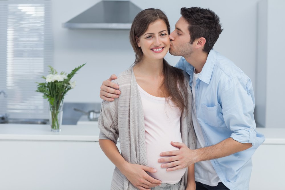 husband kisses pregnant woman's cheek