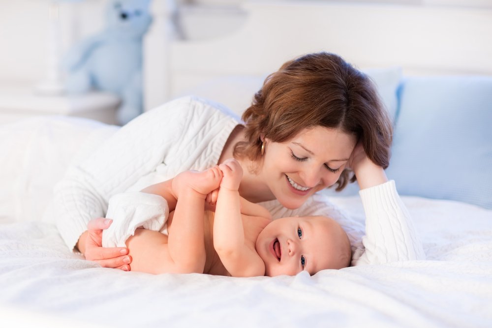 mom and baby smiling while in bed