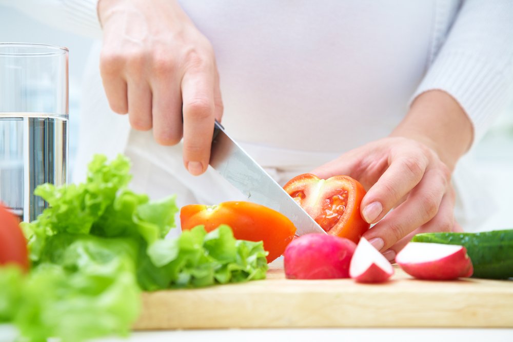 adult cutting tomatoes for a salad