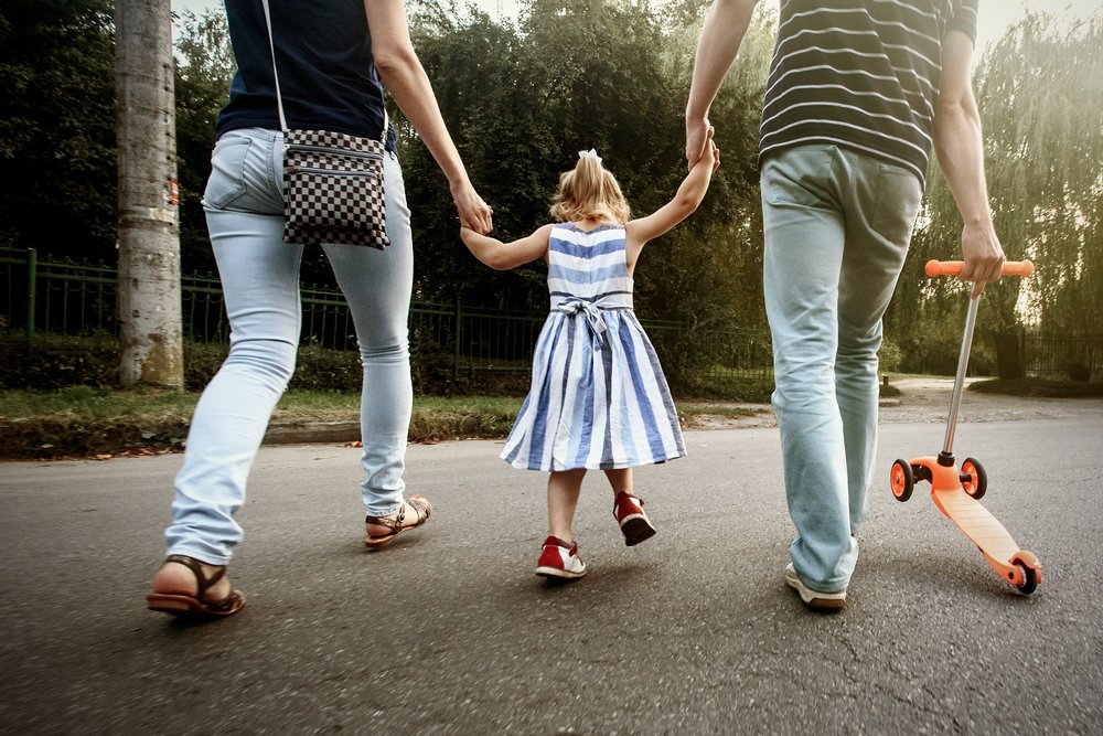 parents holding their daughter's hand while walking