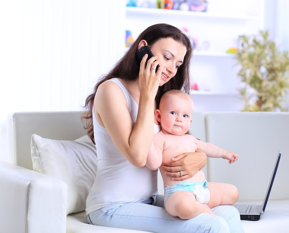 woman speaking on the phone and holding her baby