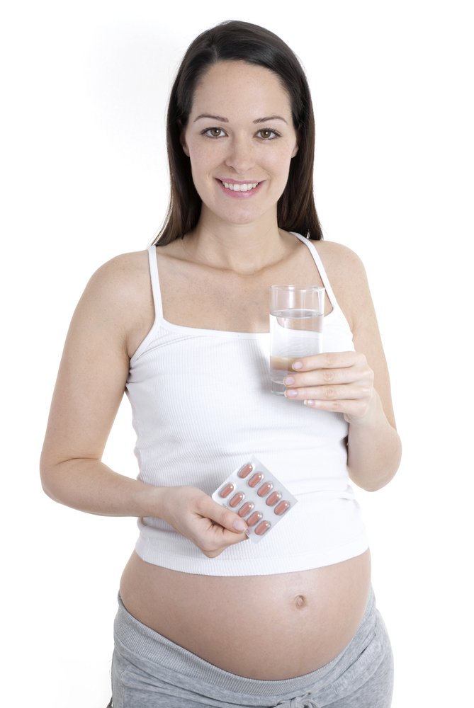 woman holding a glass of water and pills
