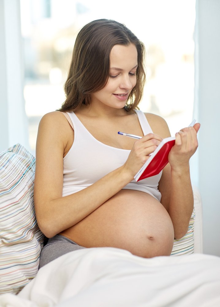 pregnant woman writing on a notebook