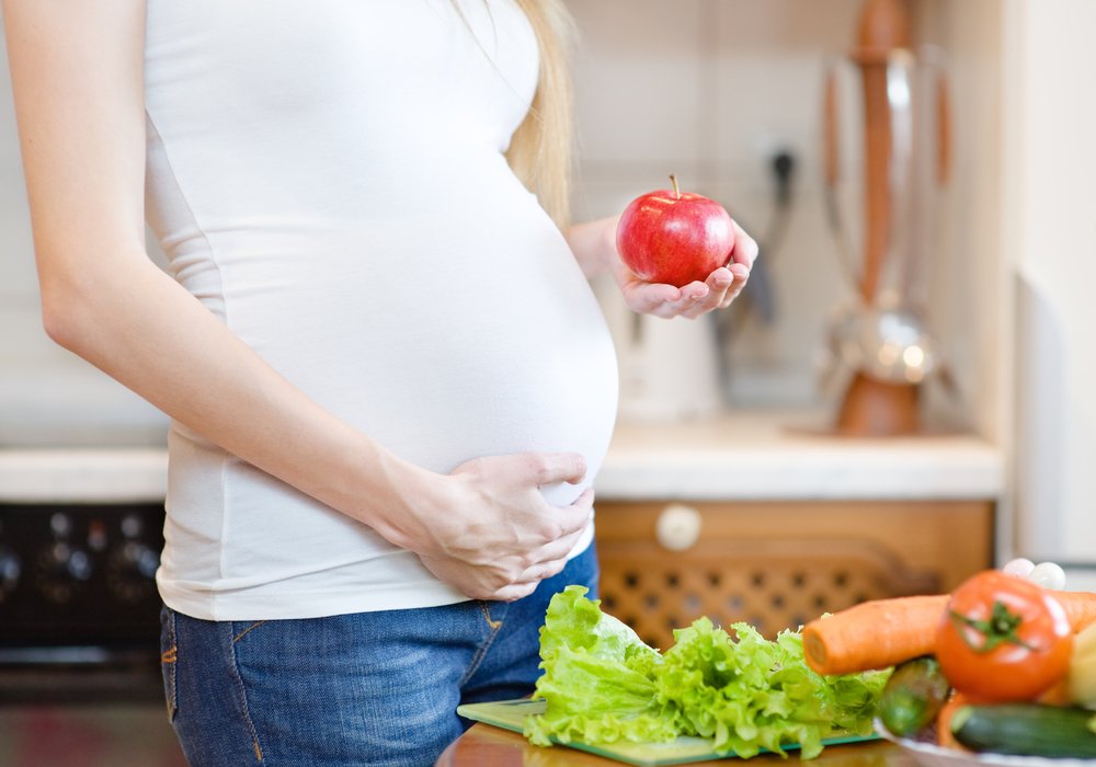 pregnant woman holding a tomato