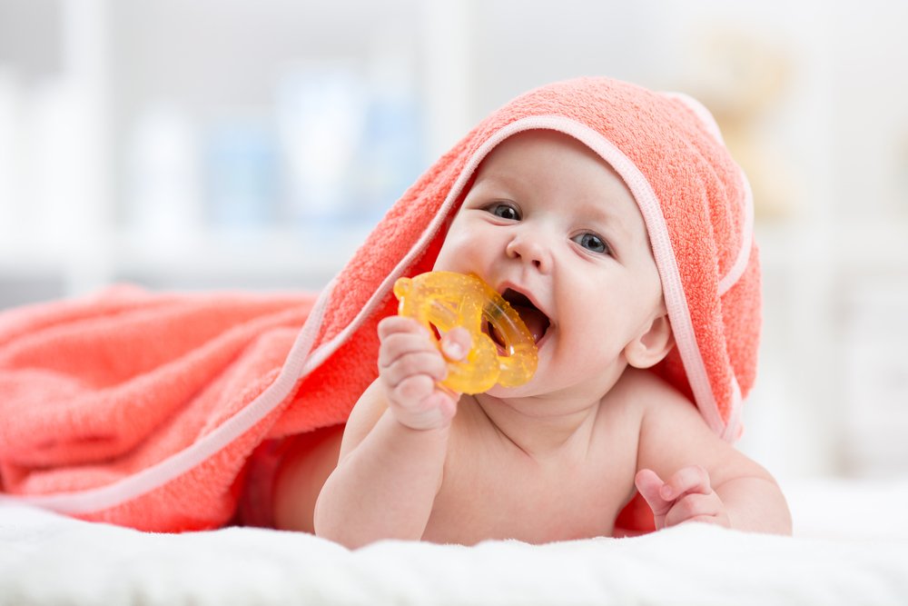 baby on his tummy mouthing a toy