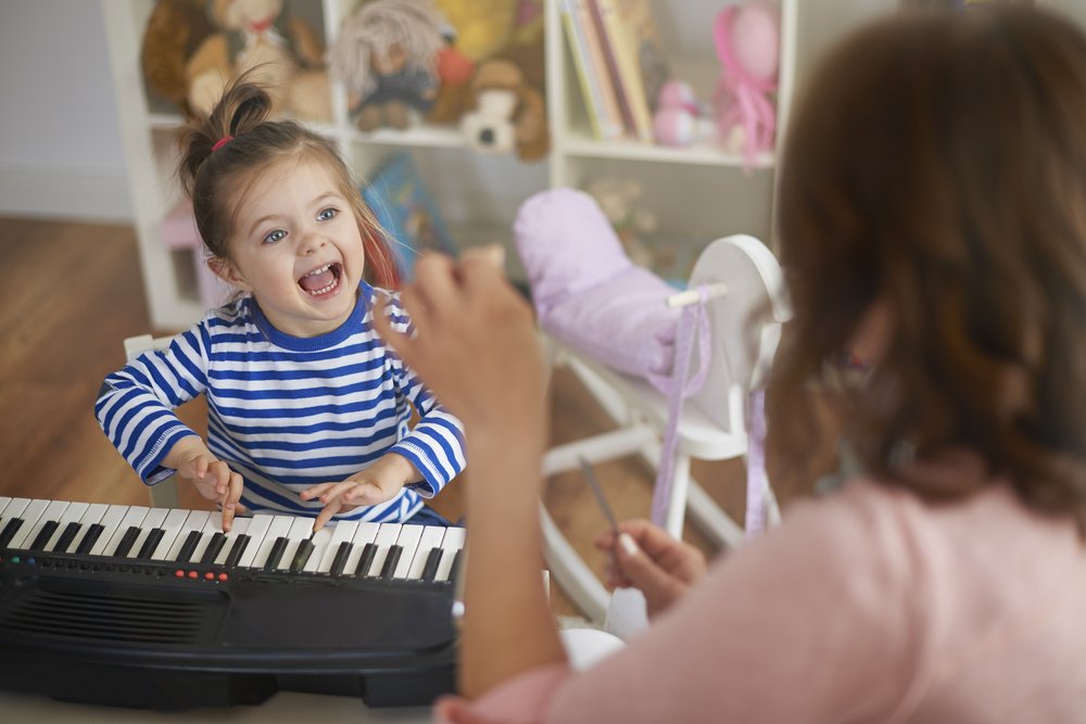 smiling girl playing with a piano
