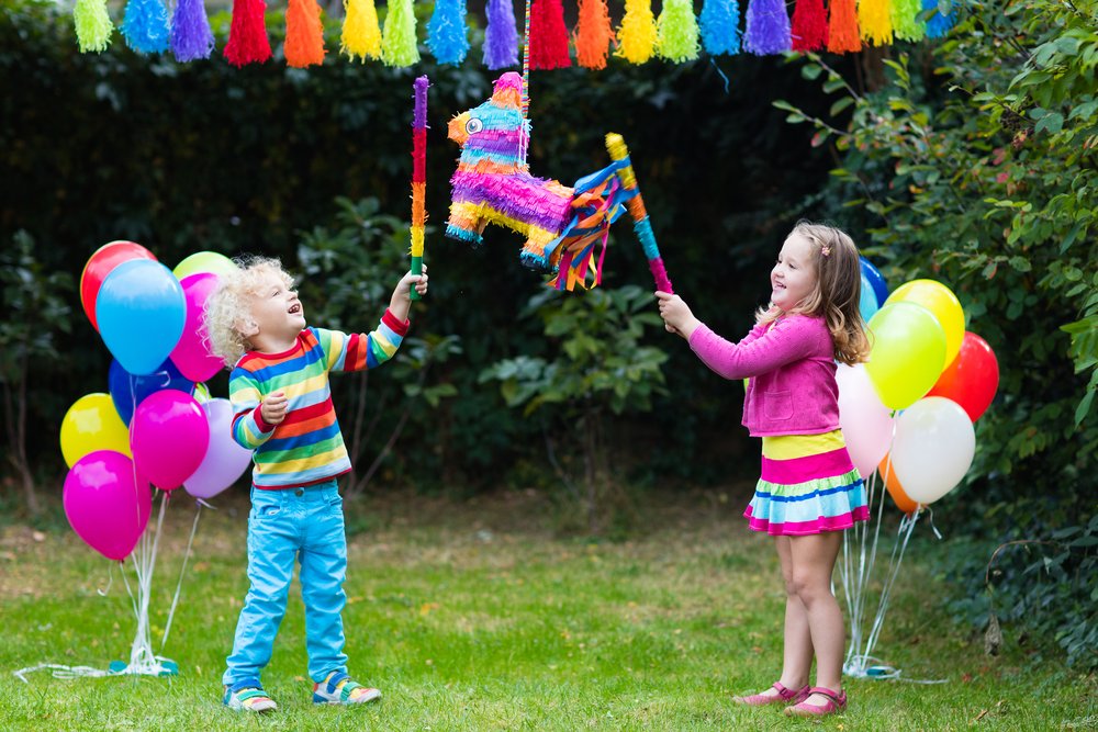 two siblings hitting a piñata in a birthday party