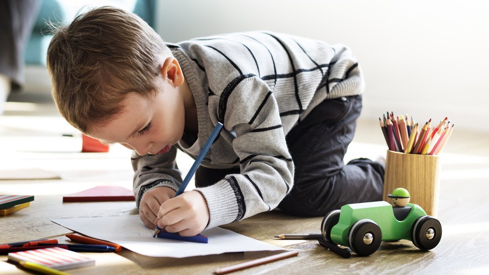 little boy scribbling with a pencil