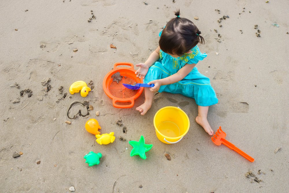 little girl playing with toys on the sand