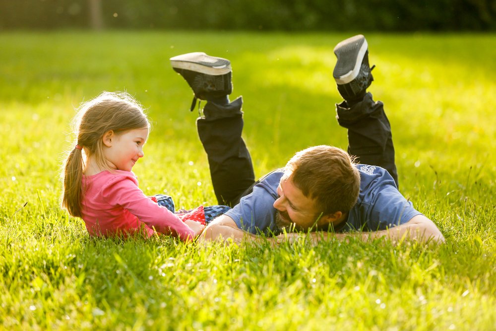 little girl laughing with her father outdoors