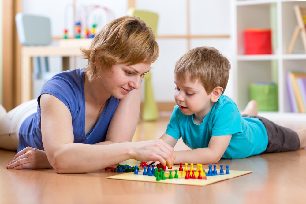 little boy playing a board game with his mom