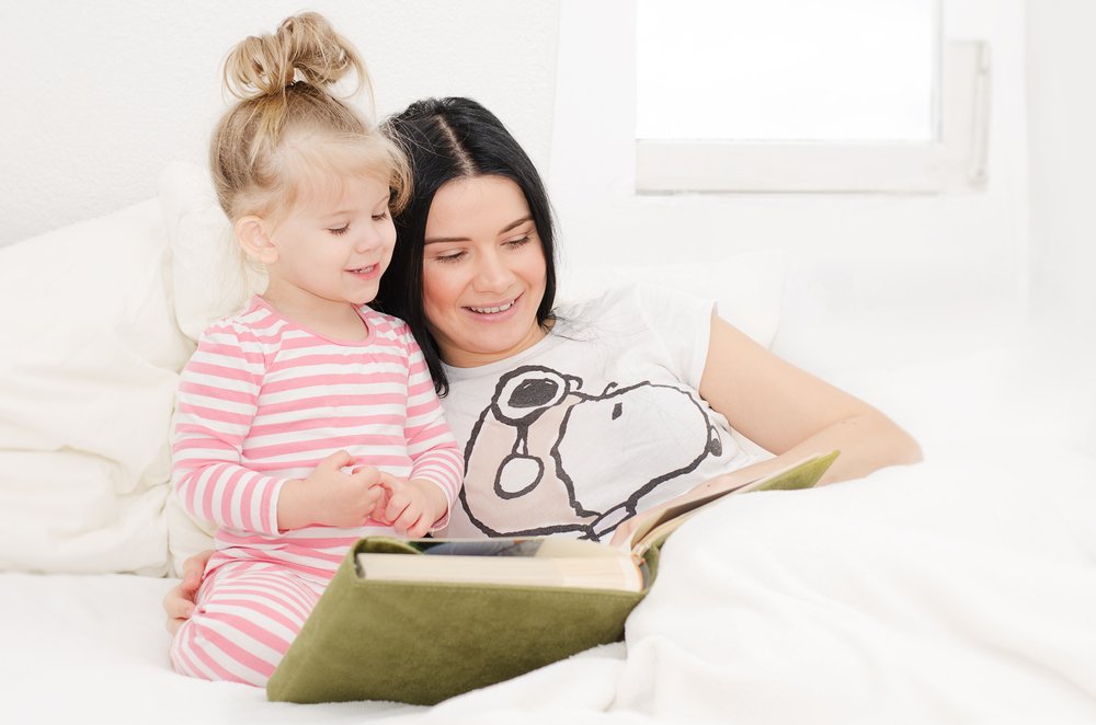 little girl reading with her mom