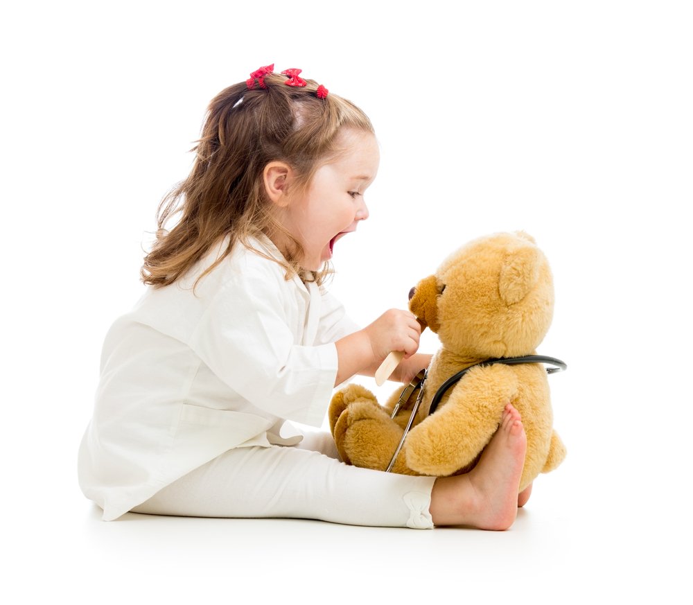 little girl playing doctor with a teddy bear