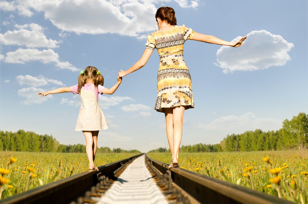 little girl and woman walking on train tracks