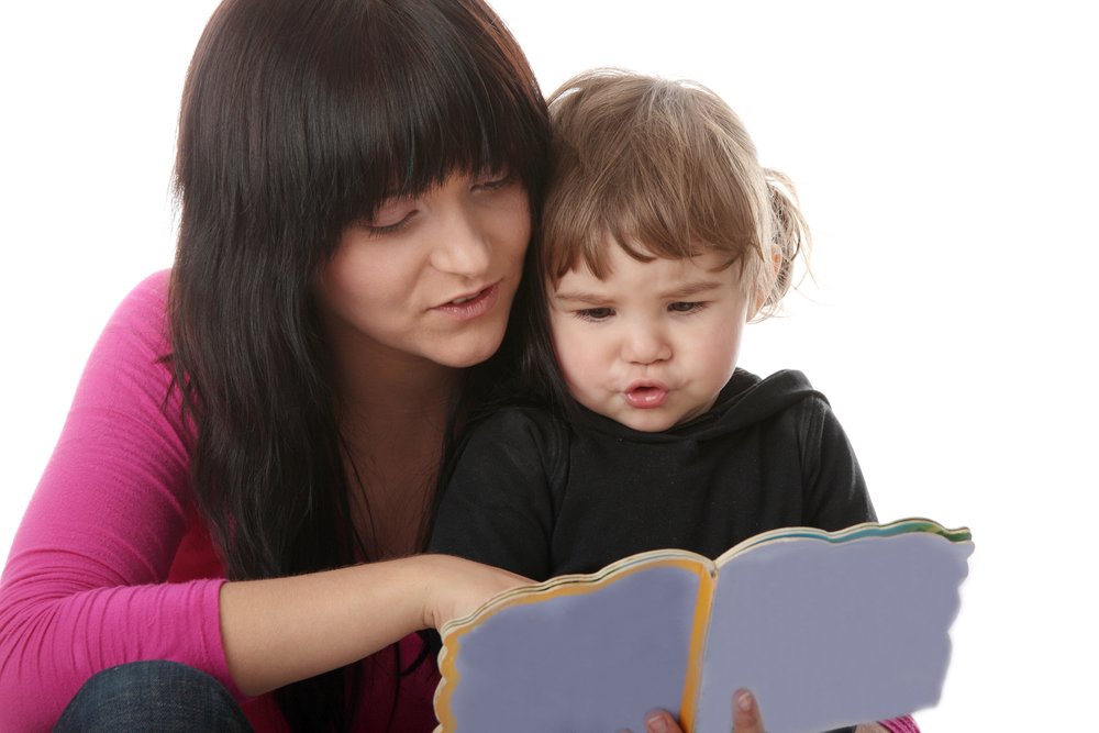 little girl reading a book with mom
