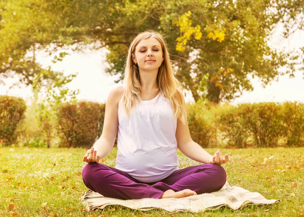 pregnant woman meditating outdoors