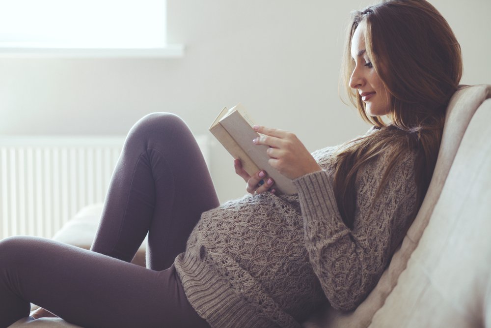 pregnant woman reading in bed