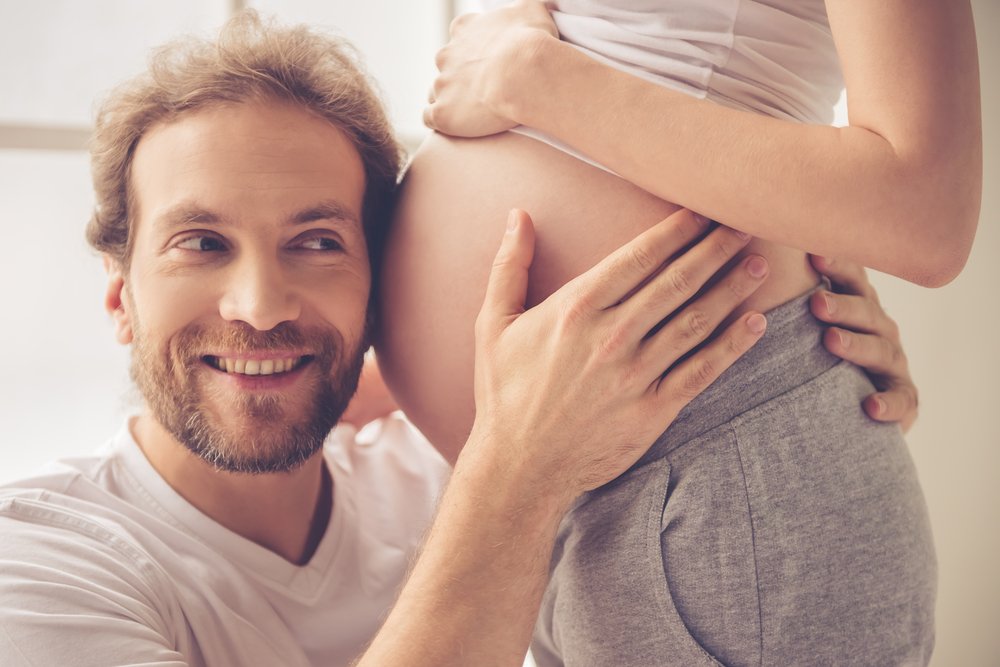 man listening to pregnant woman's belly