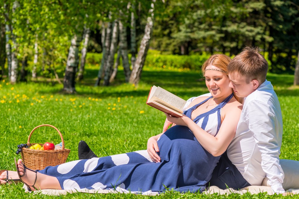 pregnant woman and partner reading outdoors