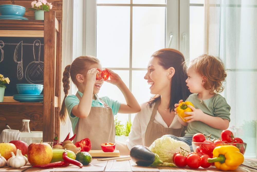 little girl, baby and mom exploring vegetables in the kitchen