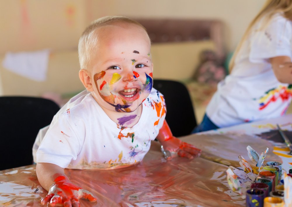 smiling baby boy covered in paint