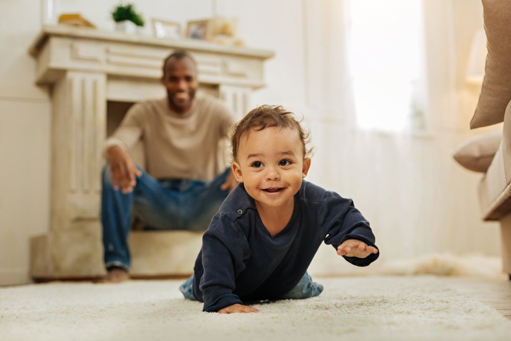 baby boy crawling while father watches