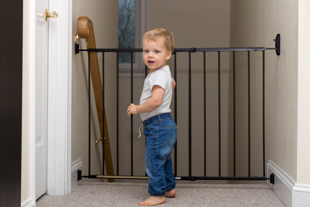 baby boy standing in front of a stair's barrier