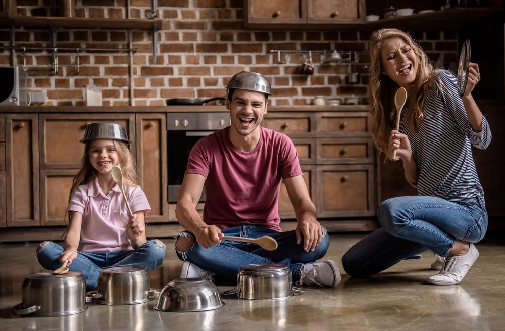 parents and little girl playing music with kitchen utensils