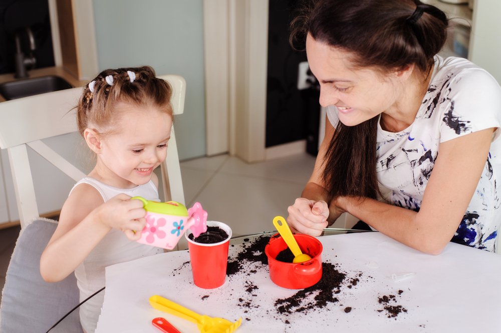 mom and little girl plating seeds in plastic cups