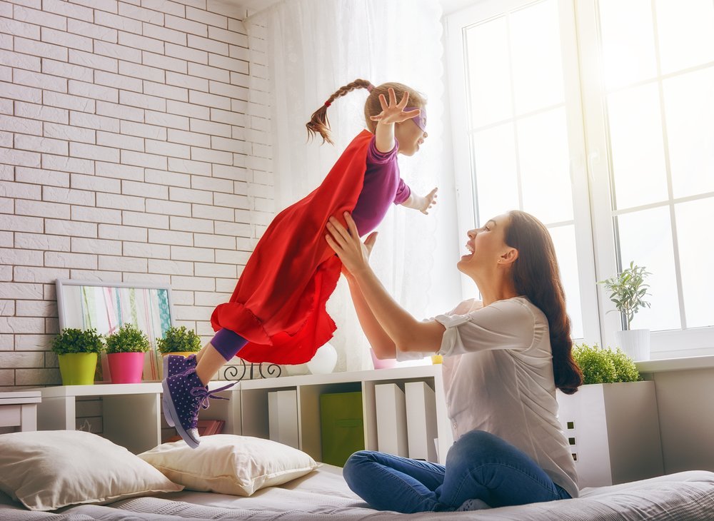 little girl in a cape jumping to her mom's arms
