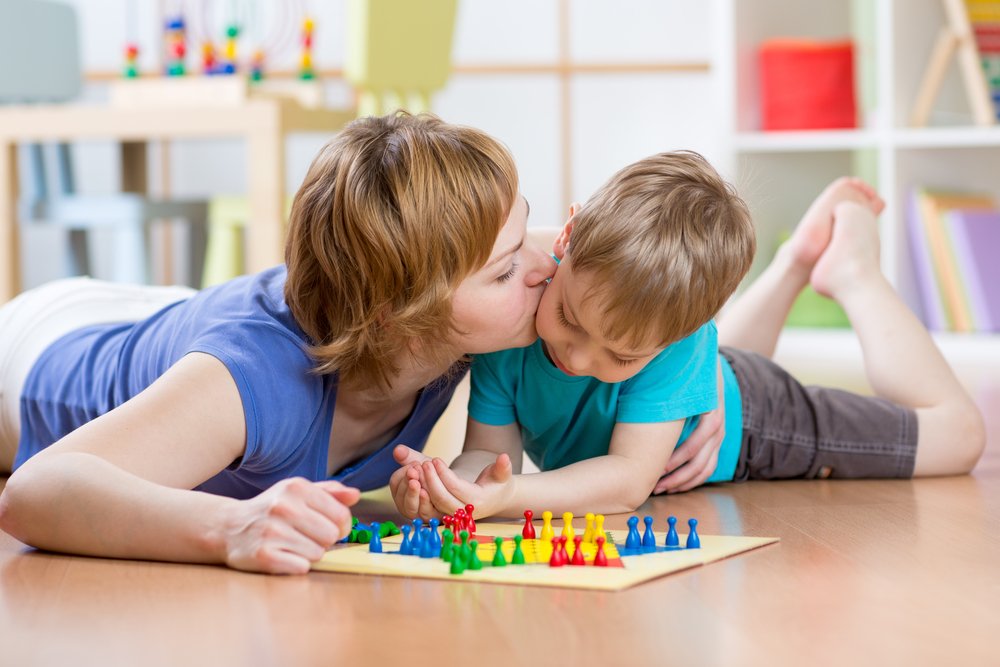 mom kissing her son while playing a board game