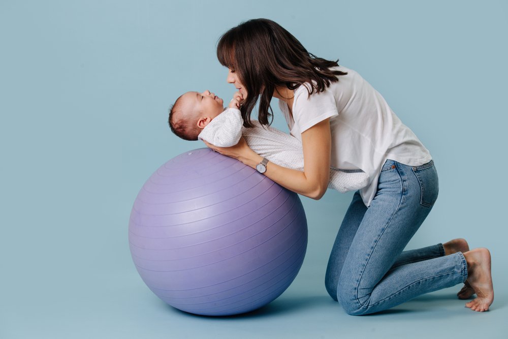 mom leaning her baby on a yoga ball