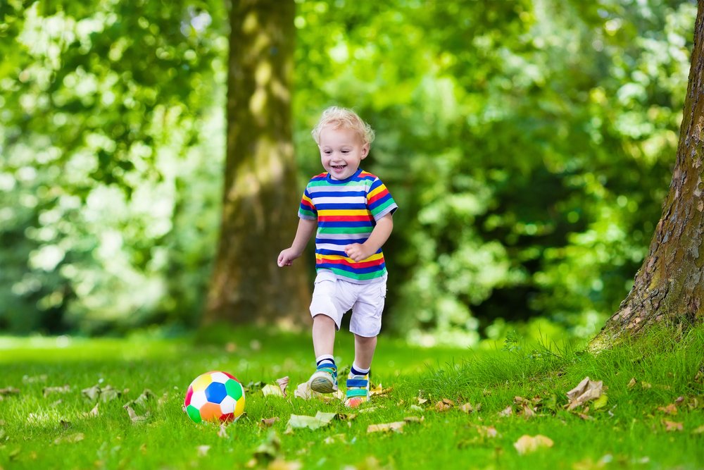 little boy running after a football